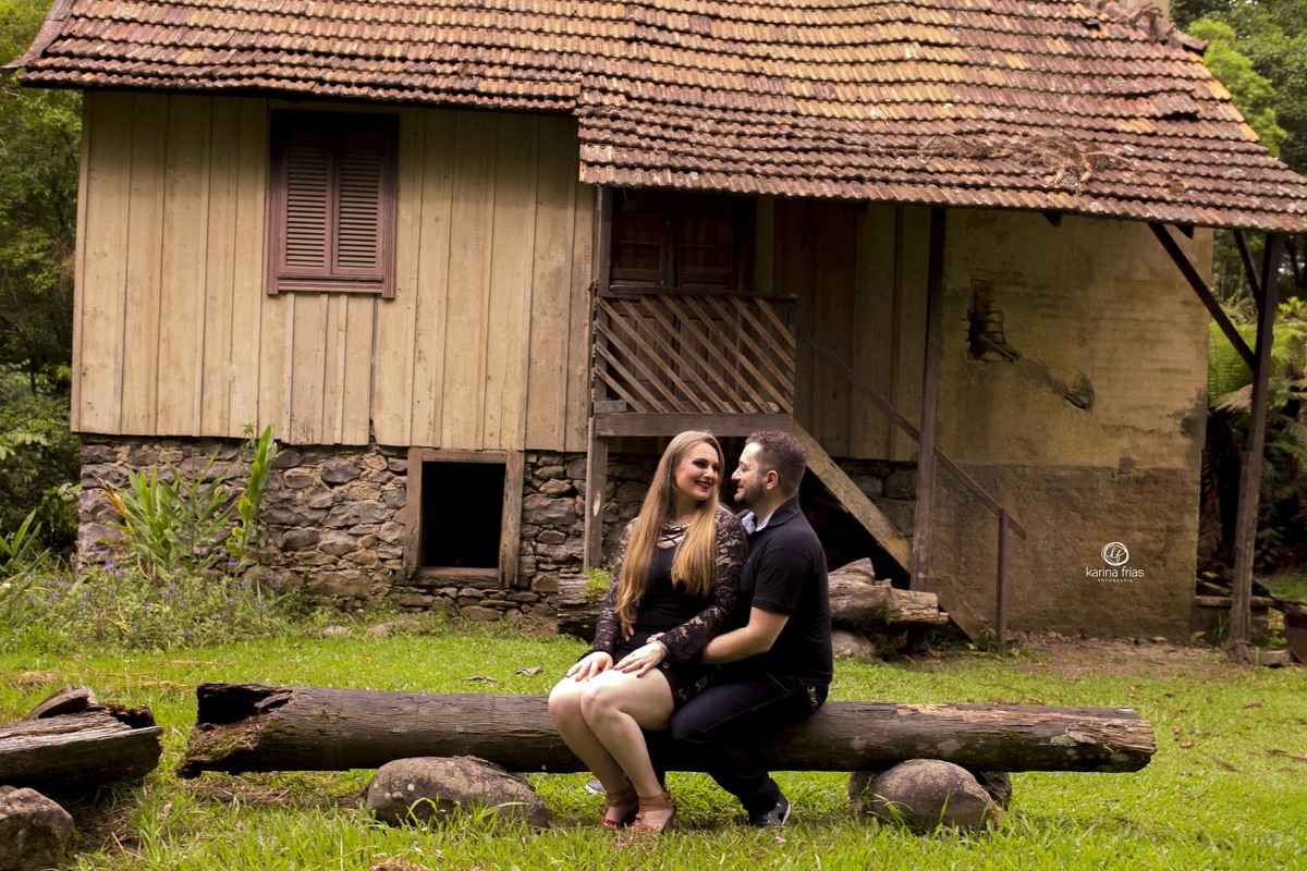 O CASAL ESTA SENTADO COM A CASA AO FUNDO