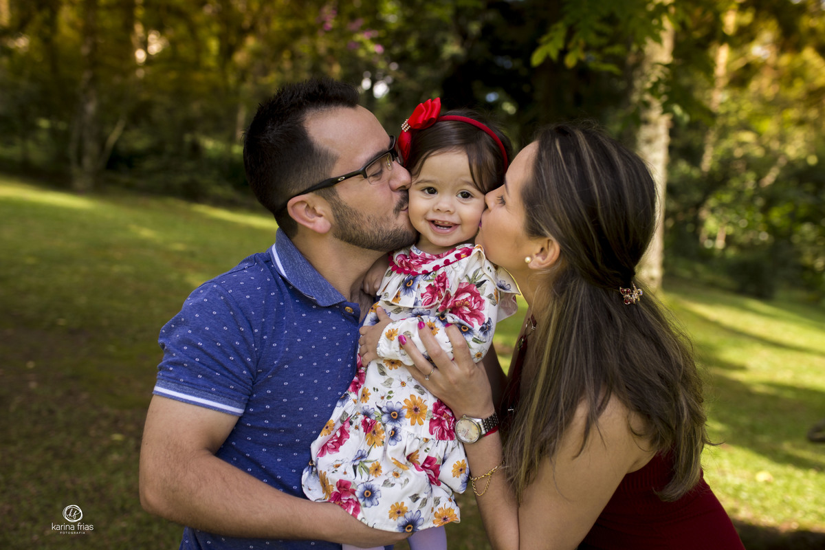 os pais beijam a criança no ensaio externo de familia