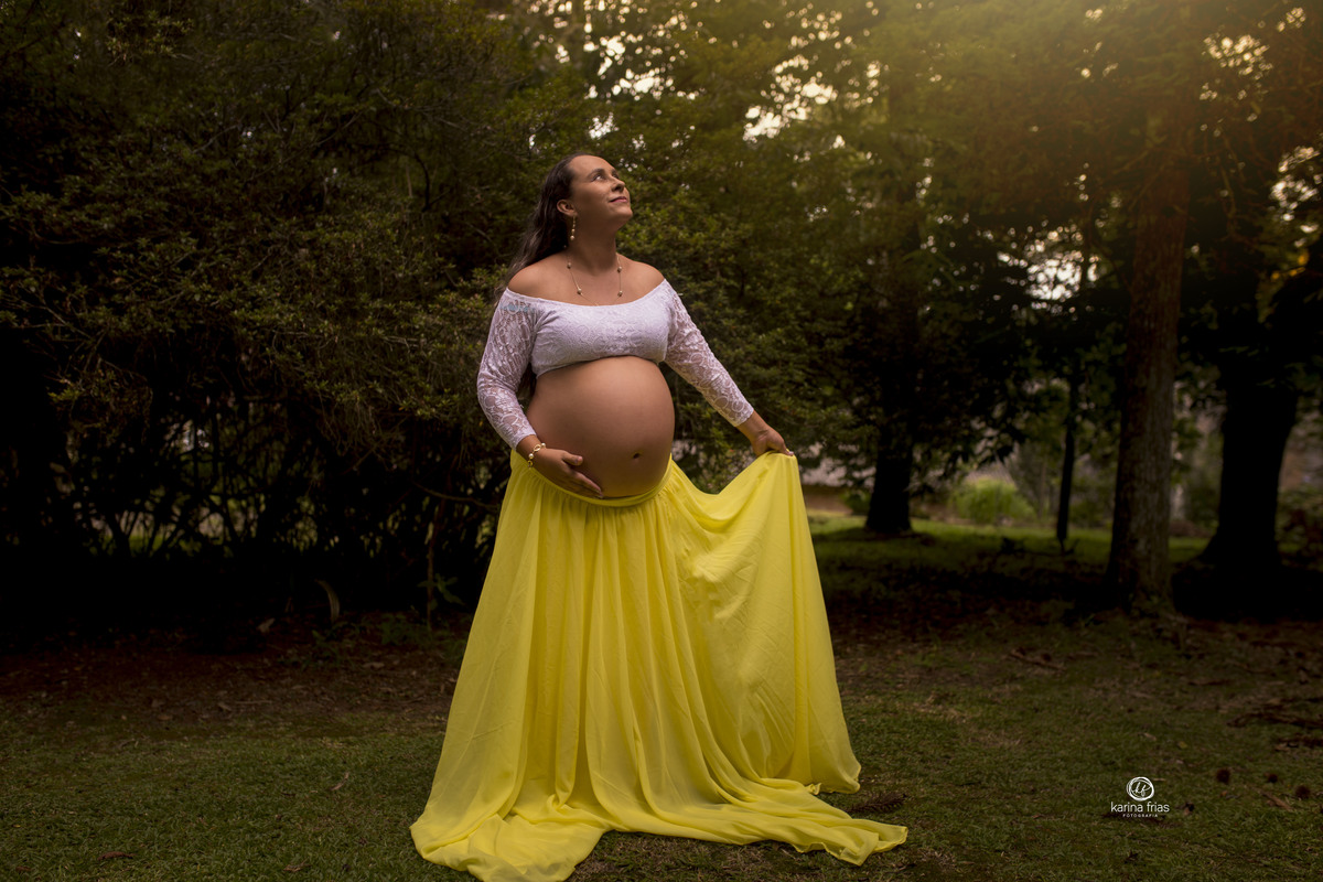 a gestante segura a saia para as fotos externas