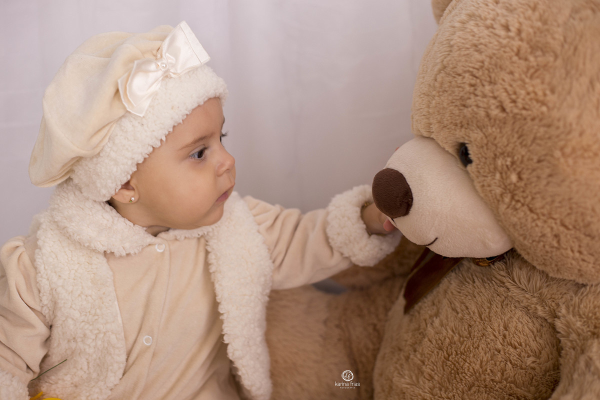 a bebe acaricia o urso nas suas fotos de 7 meses