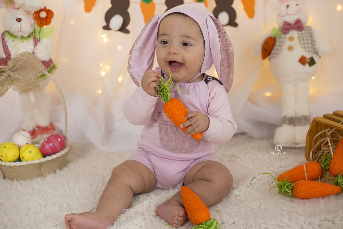 a bebe brinca com a cenoura no ensaio infantil
