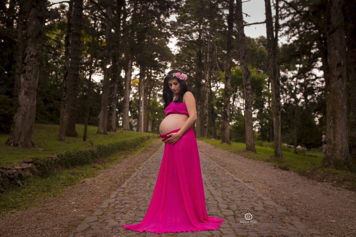 a gestante olha para a barriga durante a sessão de fotos externas