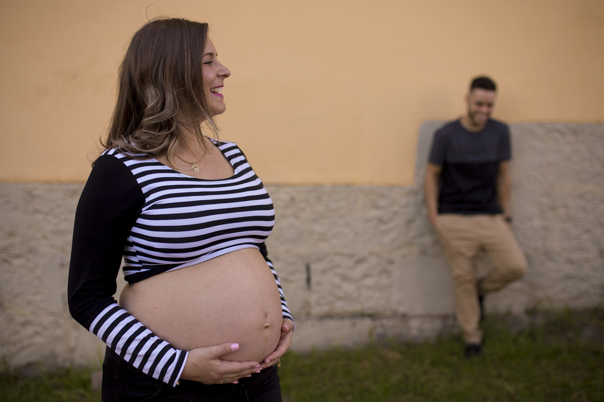 o pai esta desfocado ao fundo no ensaio de gestante