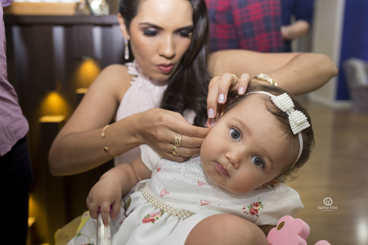 a mae coloca o brinco na filha no dia do aniversario