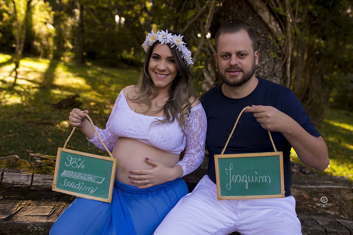 os pais seguram plaquinhas no ensaio externo de gestante