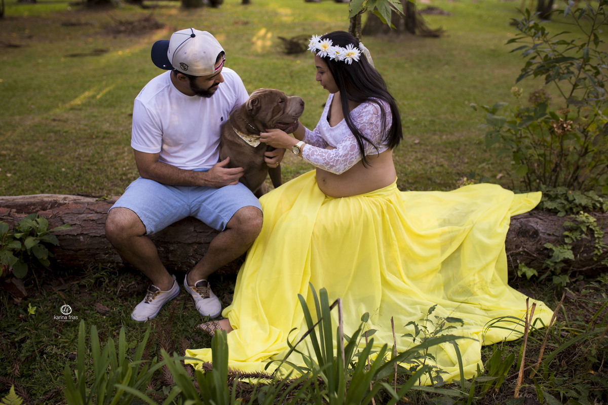 os pais brincam com o cachorro na sessão de gestante