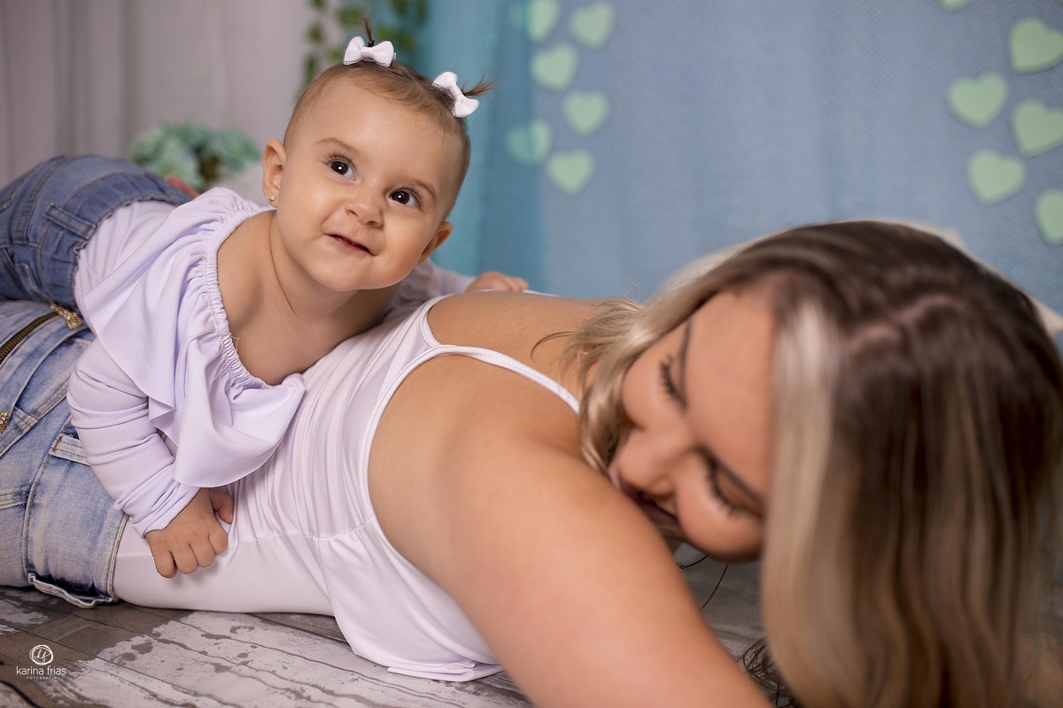 a criança esta nas costas da mae na sessão de fotos
