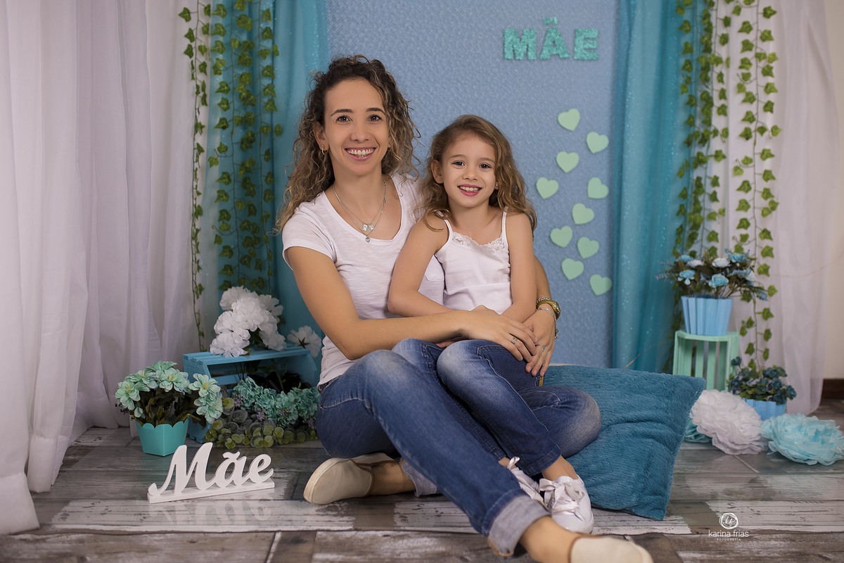 a menina esta no colo da mae na sessão de fotos