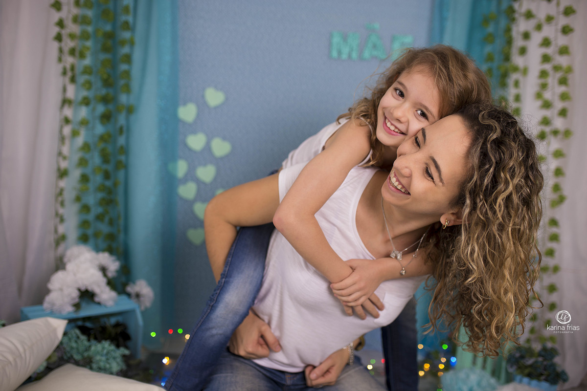 a mae pega a filha no colo enquanto a fotografa de familia de caxias do sul, registra o momento