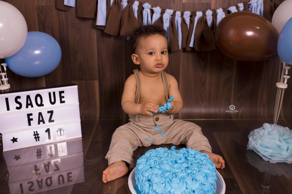 o bebe esta frente ao bolo na sessão do estudio