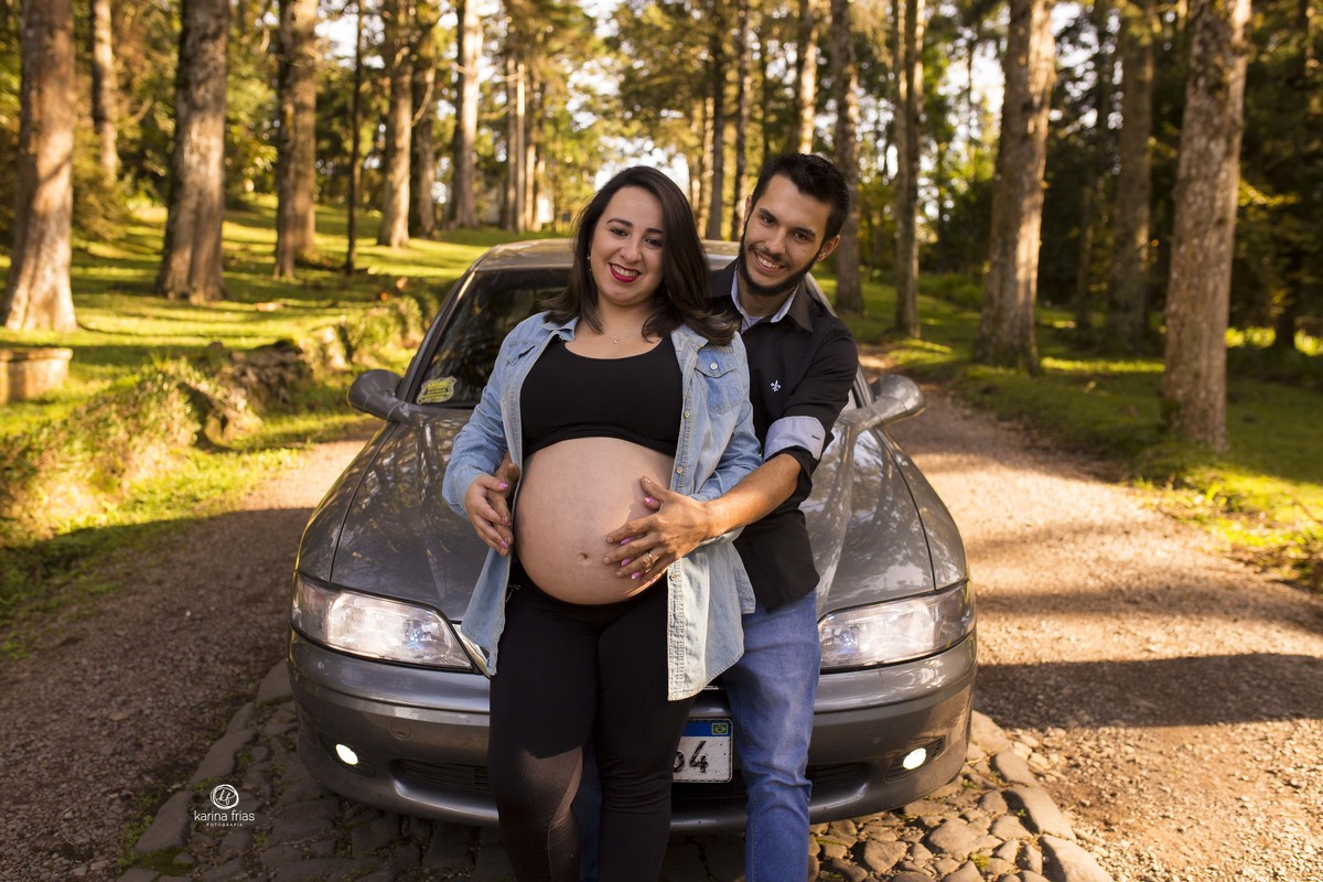 os pais posam frente ao carro para as fotos de gestante