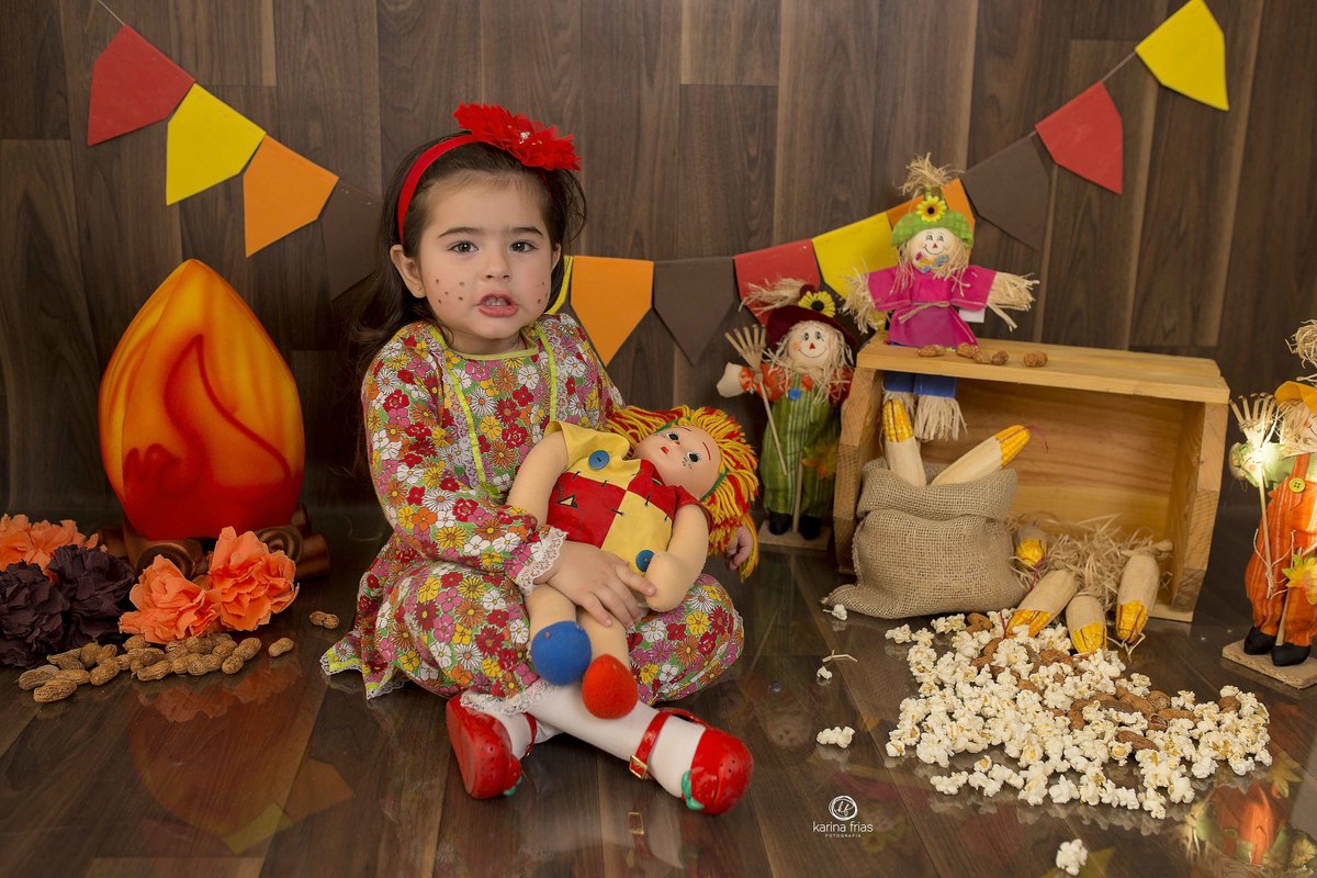 a menina esta sentada no cenario de festa junina