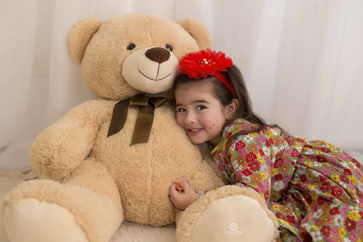 no ensaio em estudio a menina esta abraçando o urso