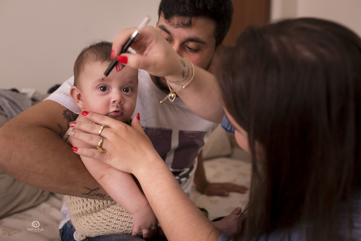 os pais pintam o menino antes da sessão de fotos