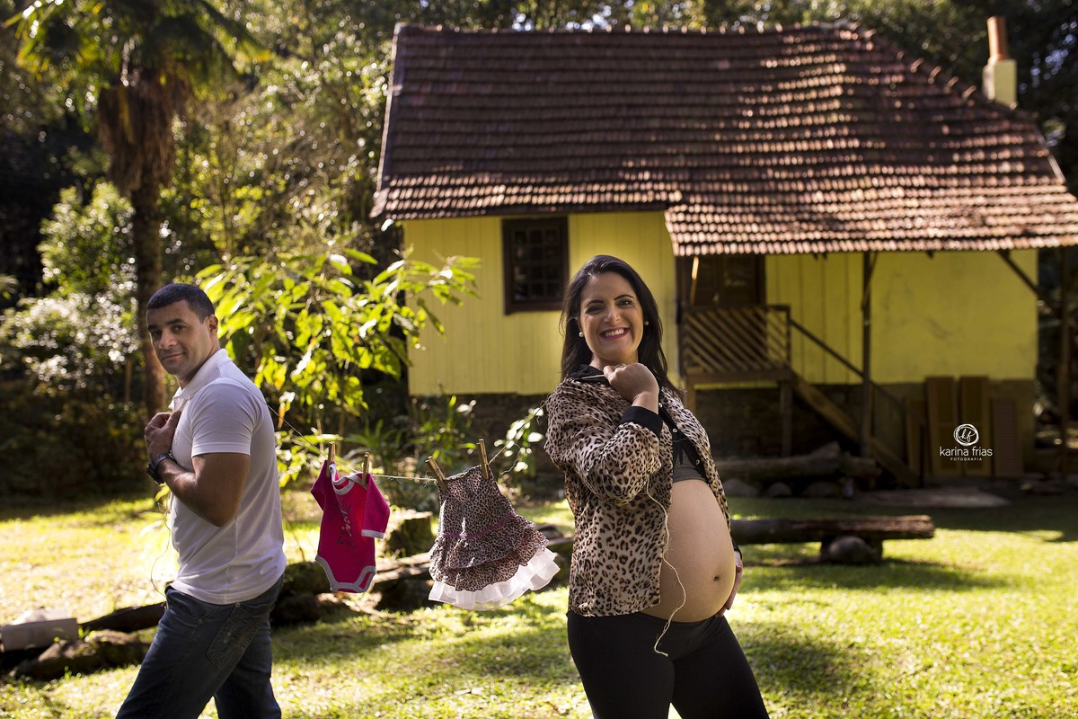 os pais estao segurando as roupinhas da bebe na sessão de fotos