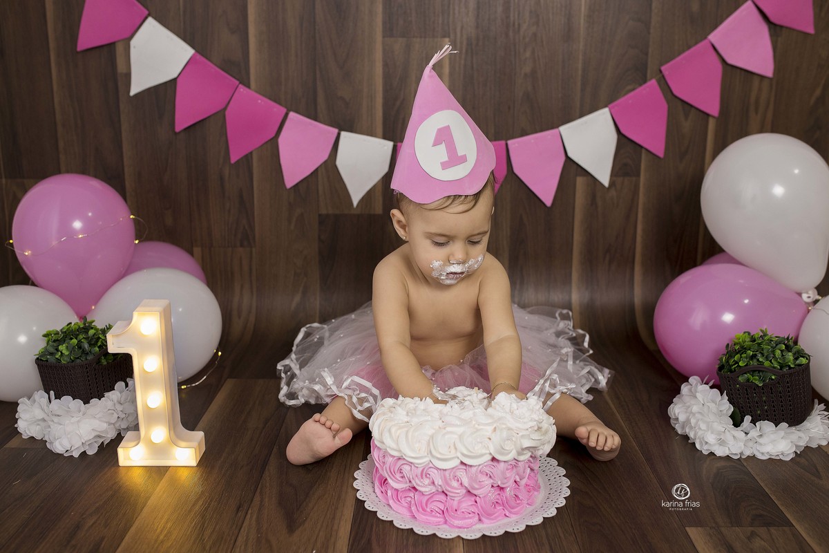 a bebe poe as duas maos no bolo do ensaio infantil