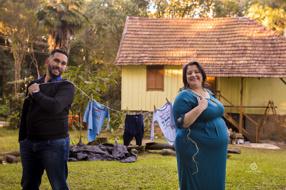 os pais seguram o varal com as roupas do bebe no ensaio