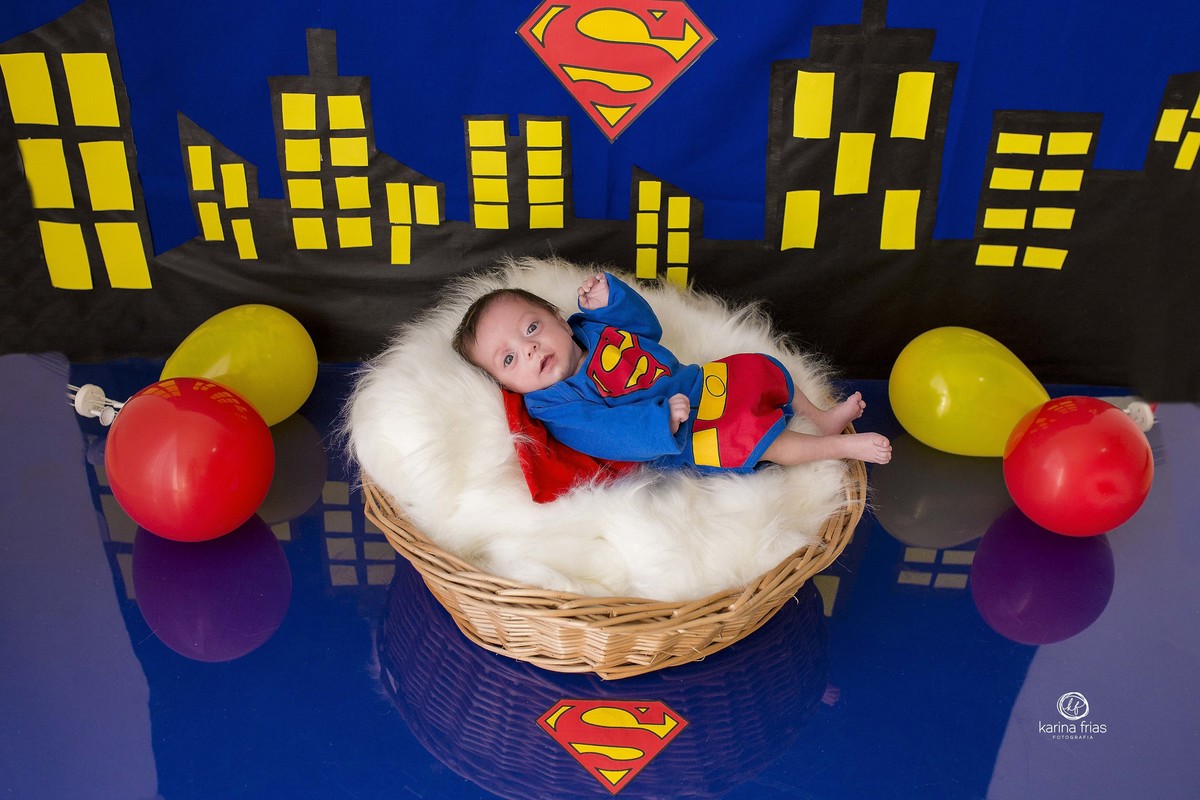 o bebe esta deitado no cenario de super homem 