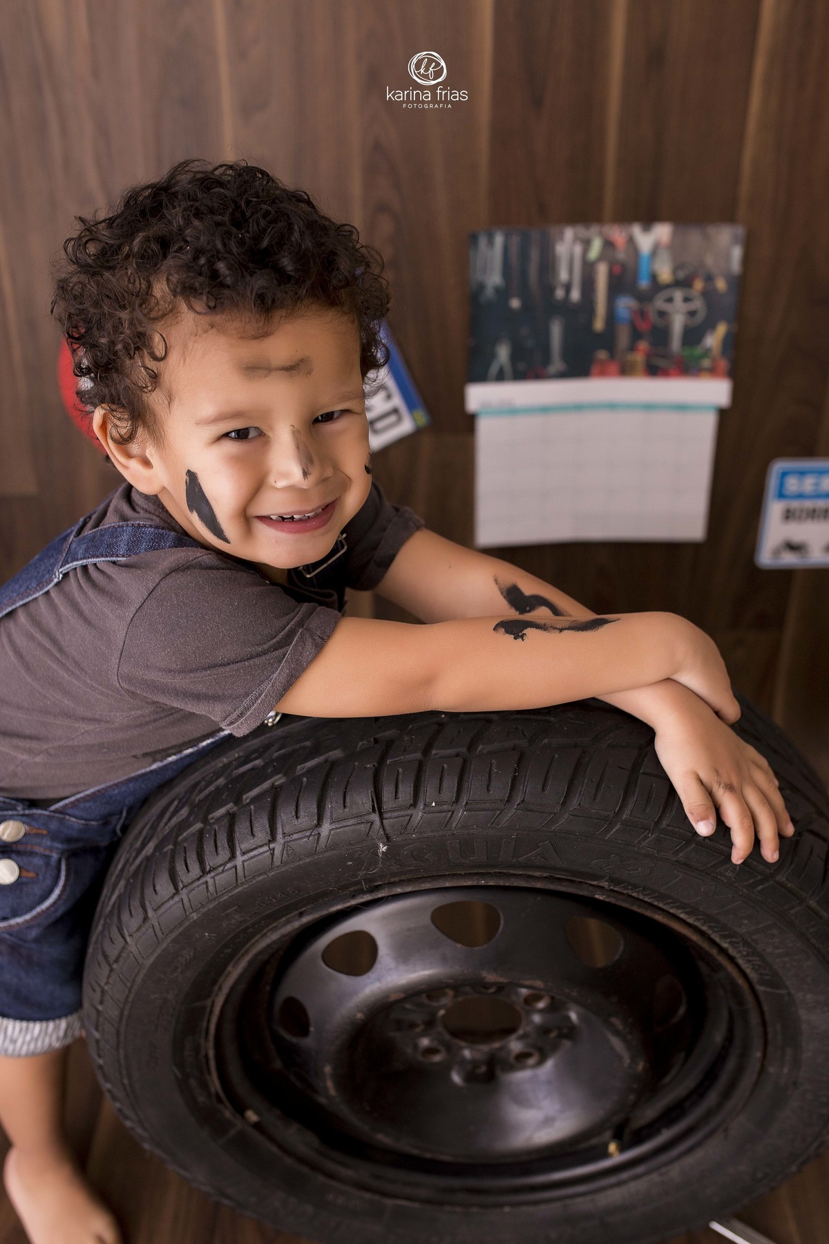 a criança se apoia no pneu durante as fotos em estudio