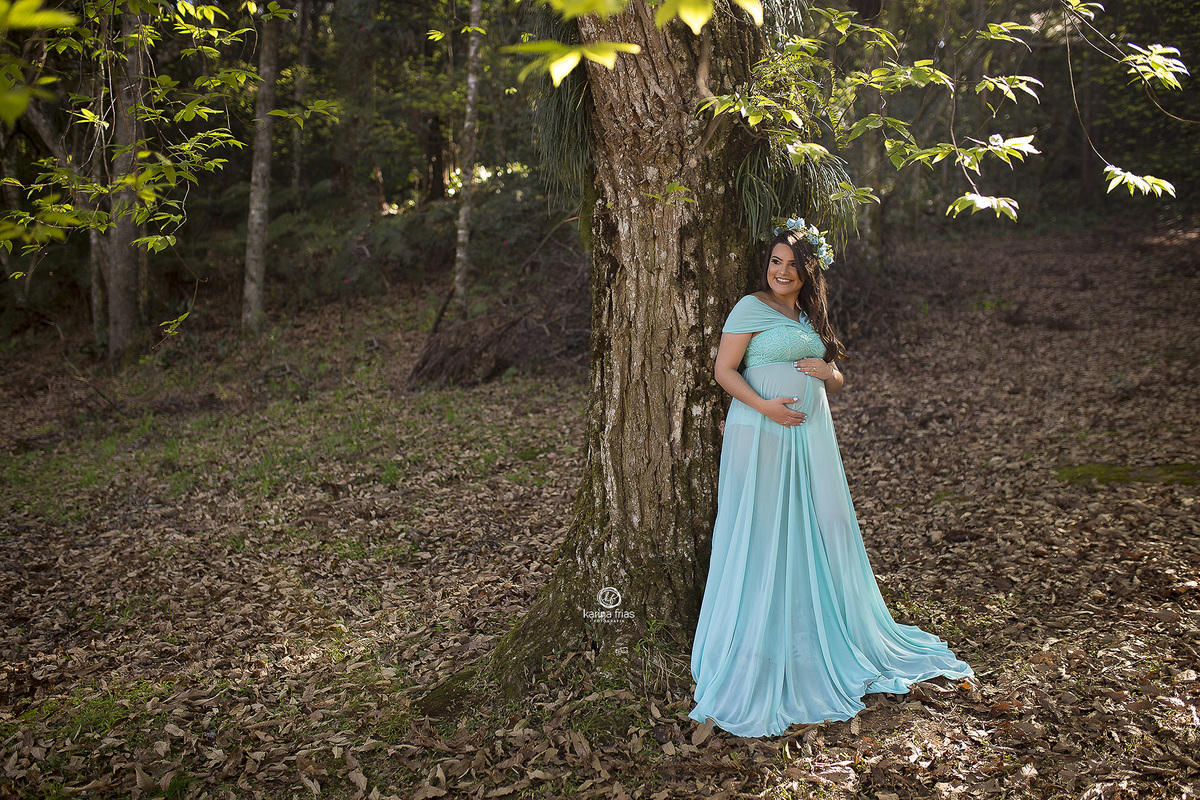 a gestante esta apoiada na arvore para as fotos externas