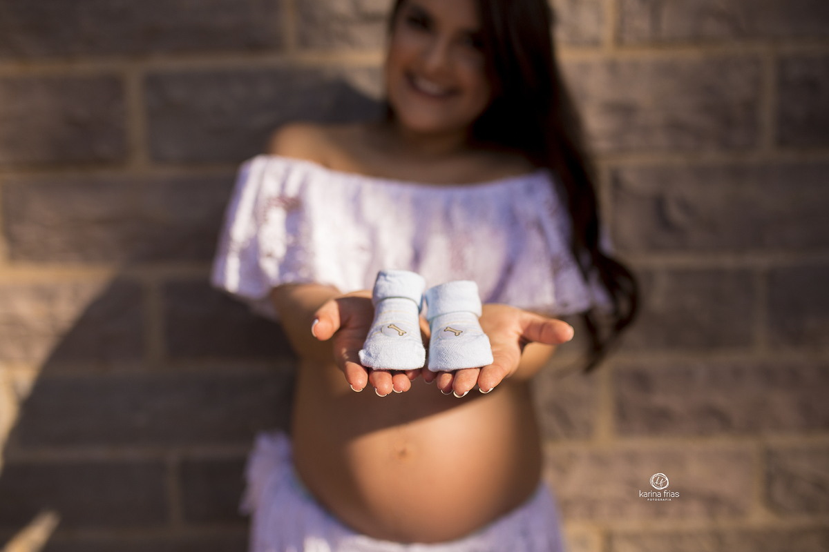 a gestante mostra os sapatinhos do bebe