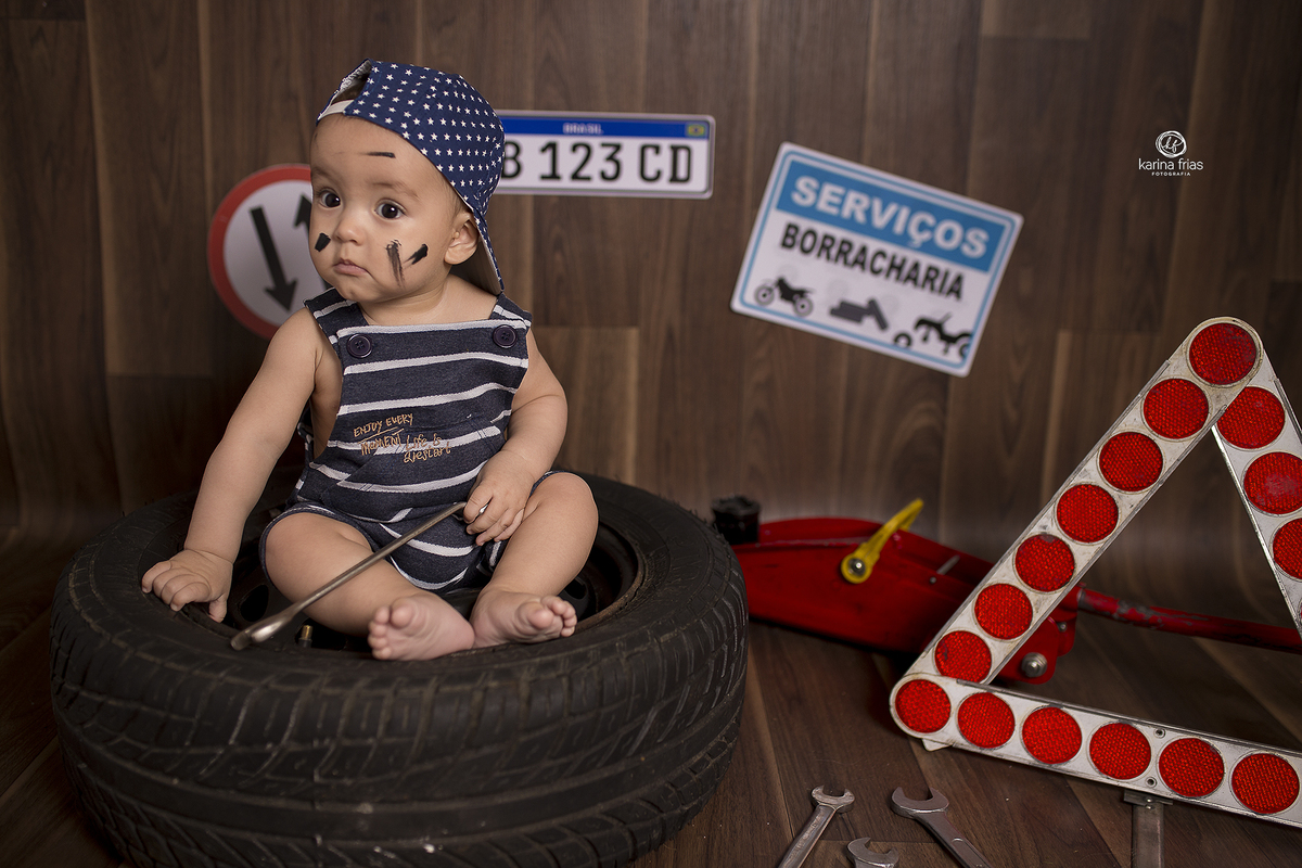 o bebe esta sentado dentro do pneu no cenario de mecanico