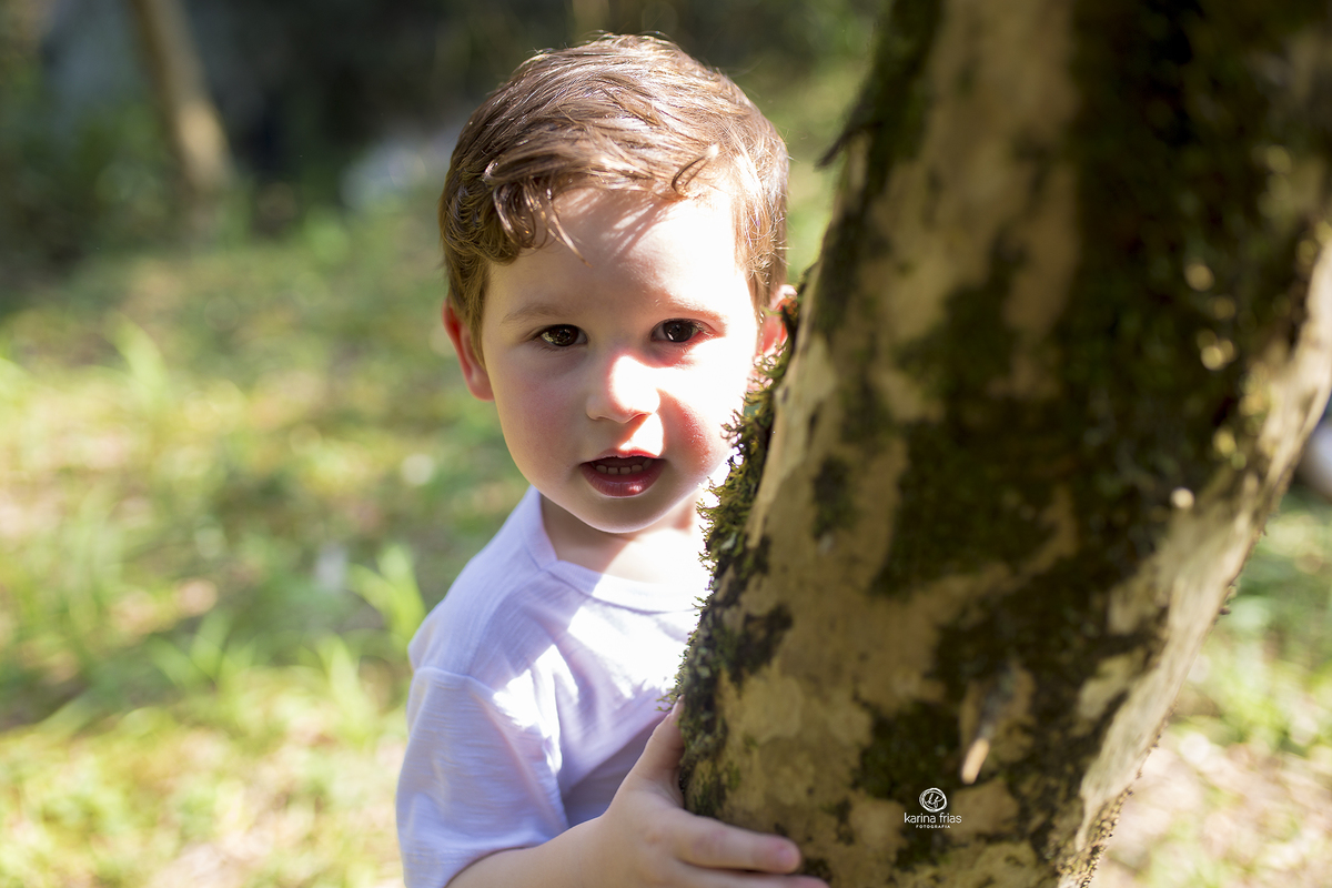 a criança se esconde atras da arvore para as fotos de familia