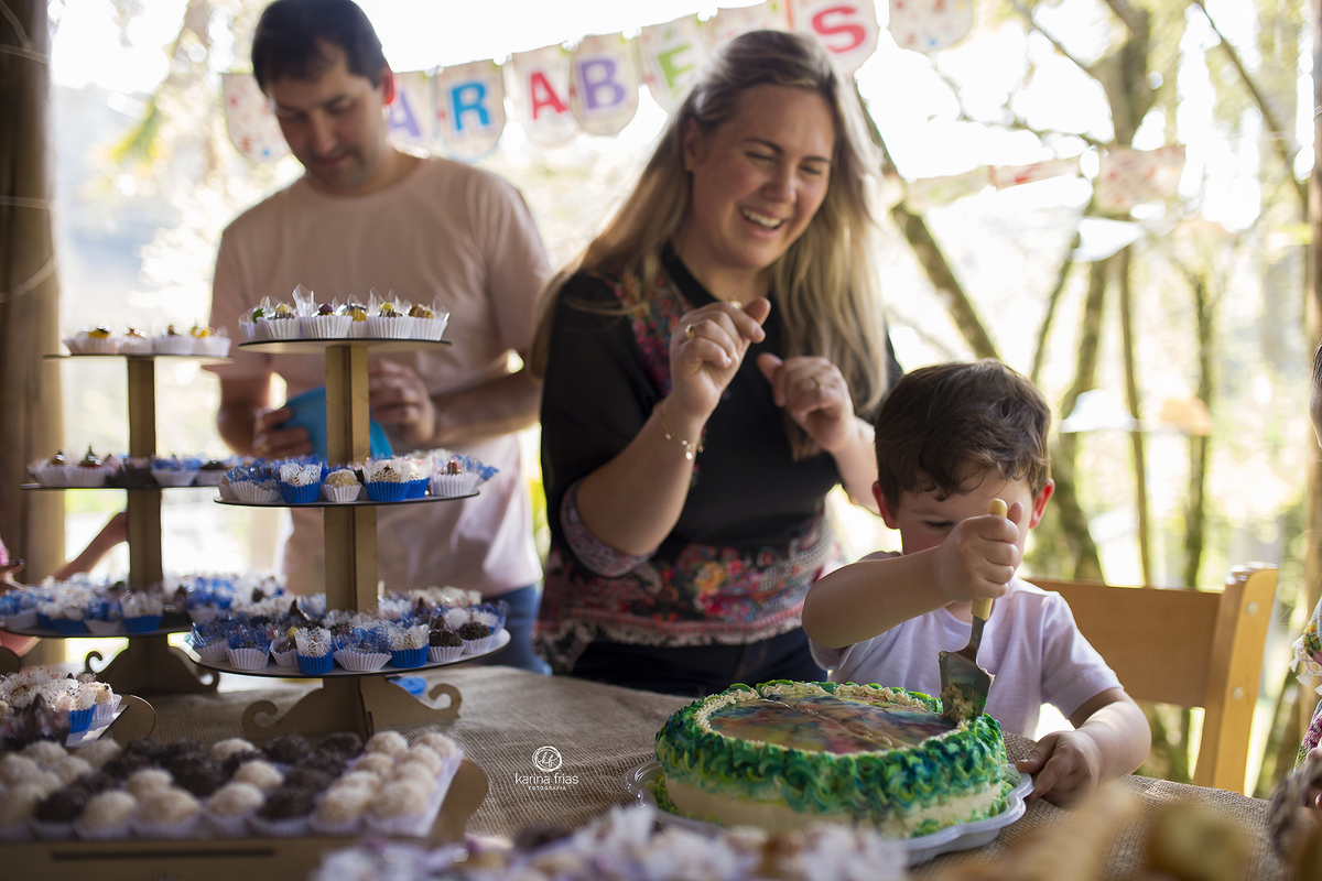 o menino corta o bolo durante as fotos de aniversario