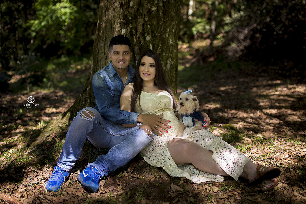 os pais estao sentados embaixo da arvore para o ensaio de gestante