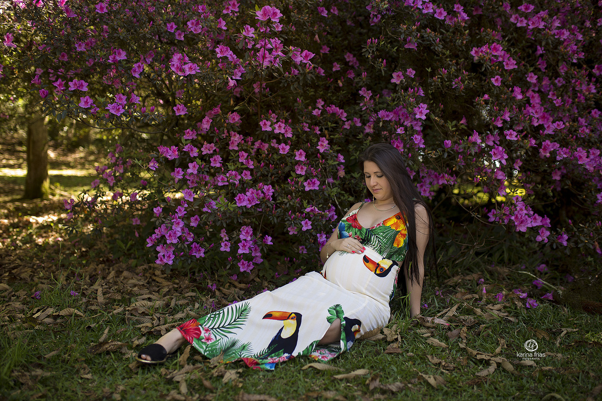 a gestante esta sentada na grama no meio das flores da primavera