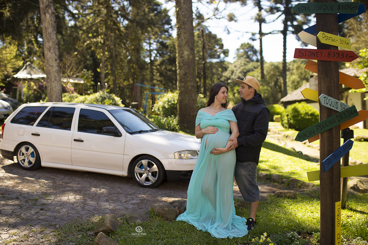 os pais posam perto do carro e de placas de direção no ensaio de gestante