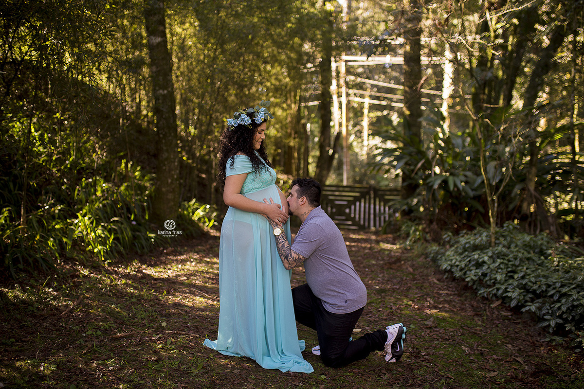o pai esta beijando a barriga da gestante na sessão de fotos