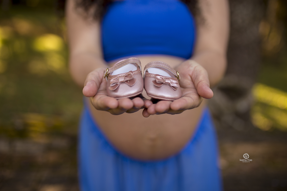 a mae segura os sapatinhos da filha e a barriga fica ao fundo