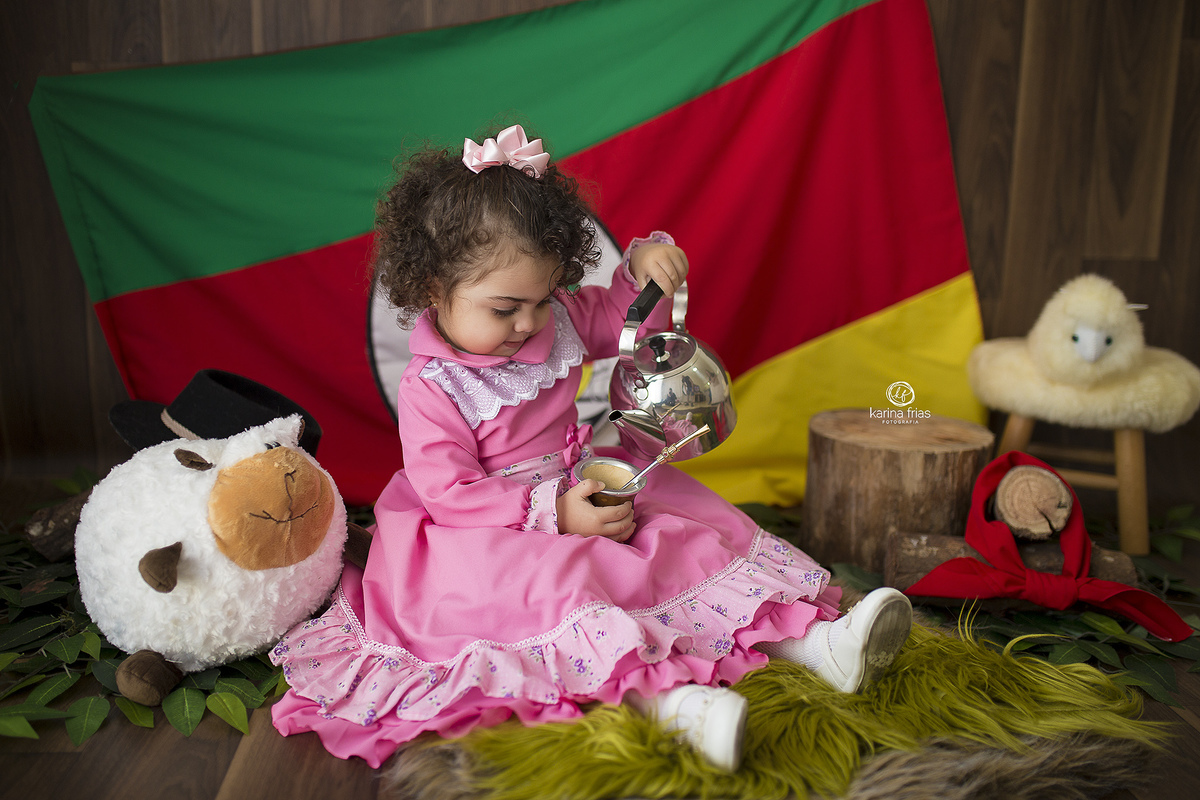 no ensaio infantil, a menina poe agua no chimarrao