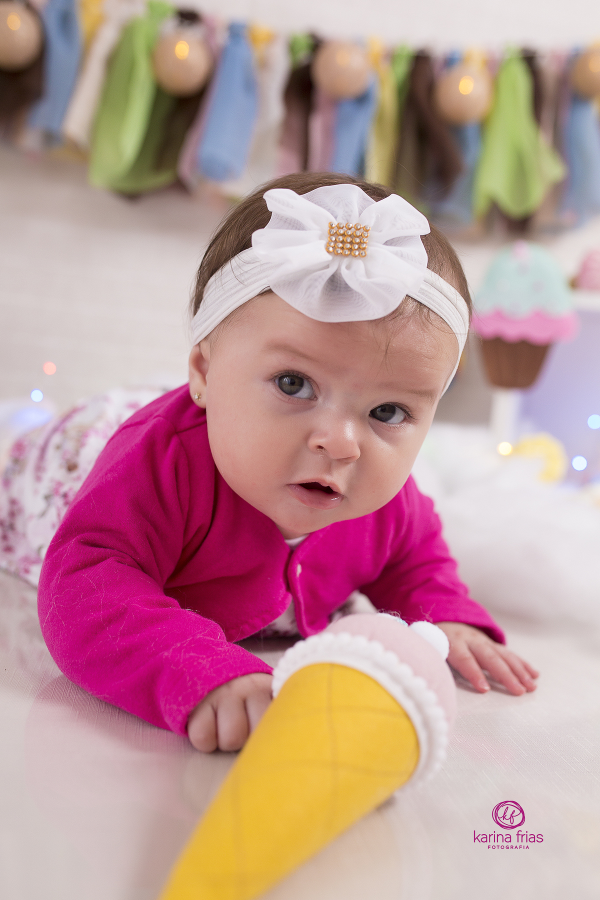 a menina esta de bruços no cenario durante a sessão de fotos