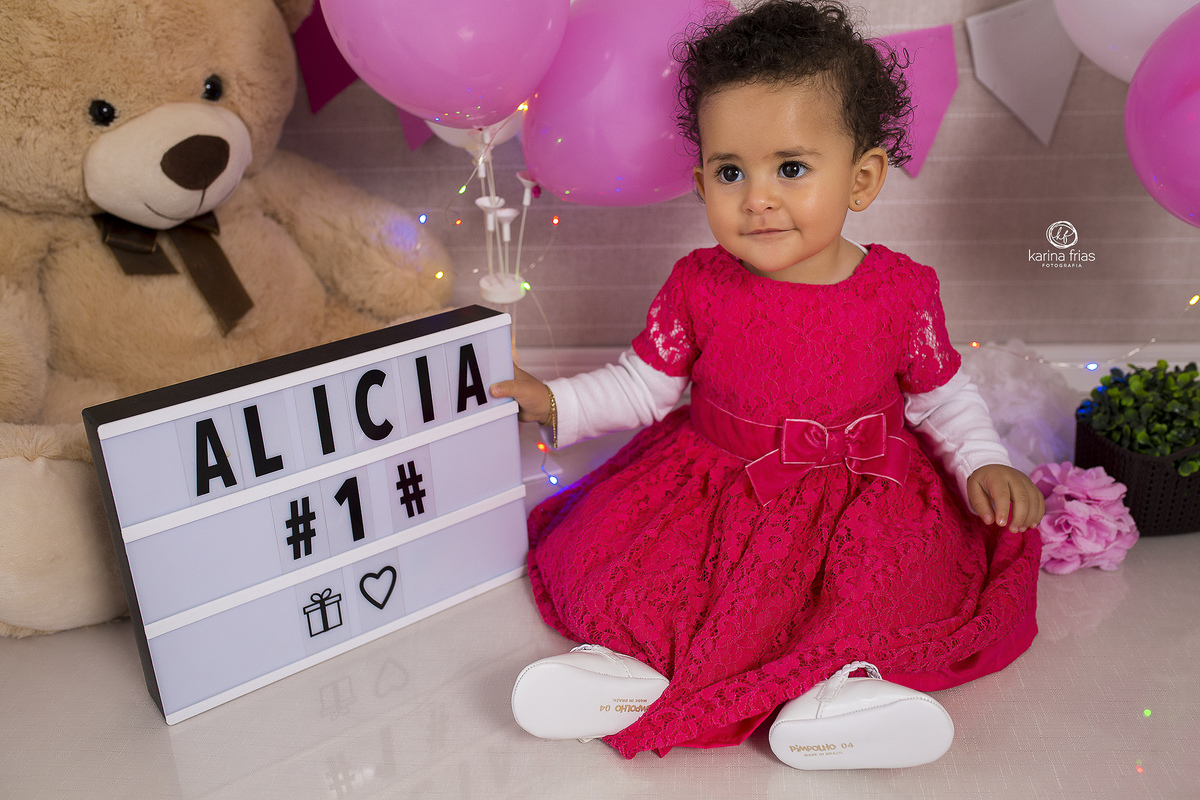 no ensaio de um ano a menina segura a placa