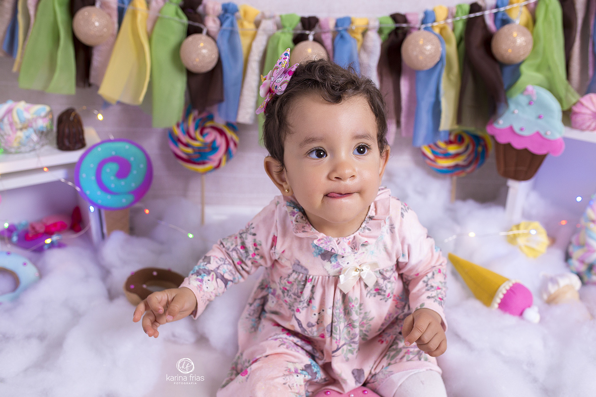 a bebe se lambuza com os doces do cenario infantil