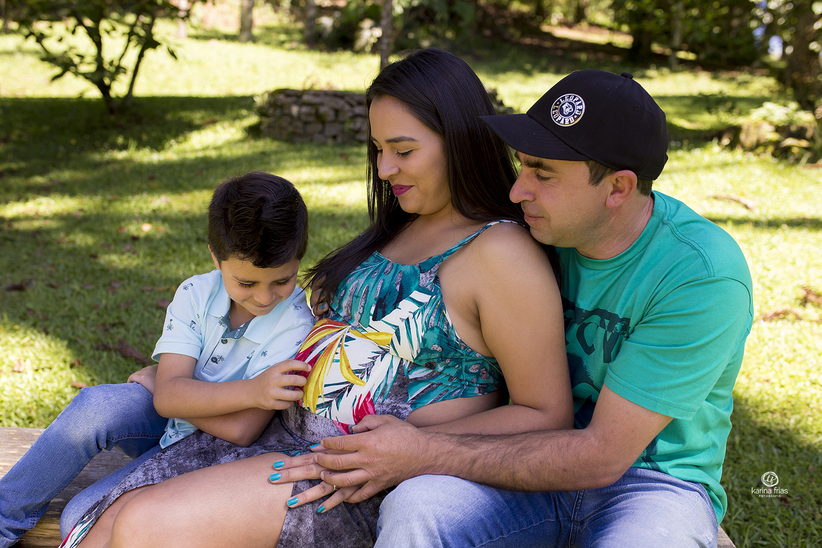 a familia olha para o filho que brinca com a barriga da mae
