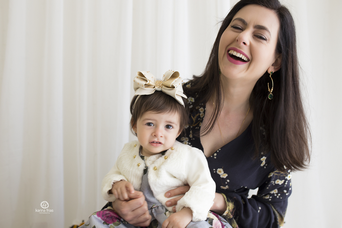 a mae sorri para a filha no ensaio infantil