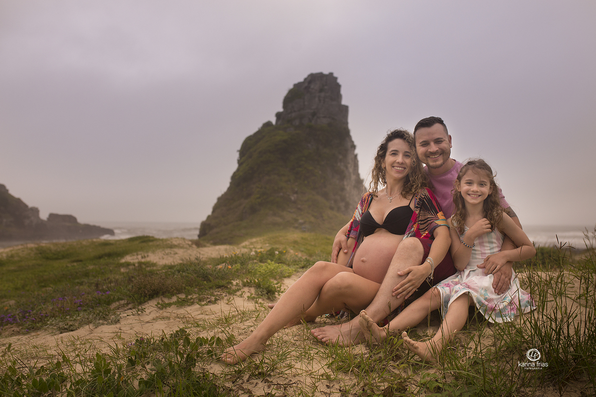 a familia senta na areia para as fotos de gestante