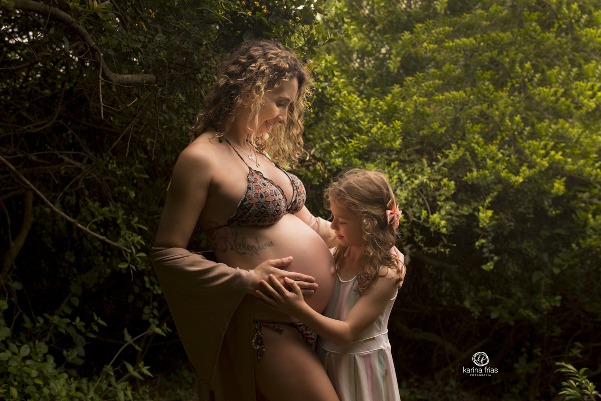 a irma mais velha olha para a barriga da mae