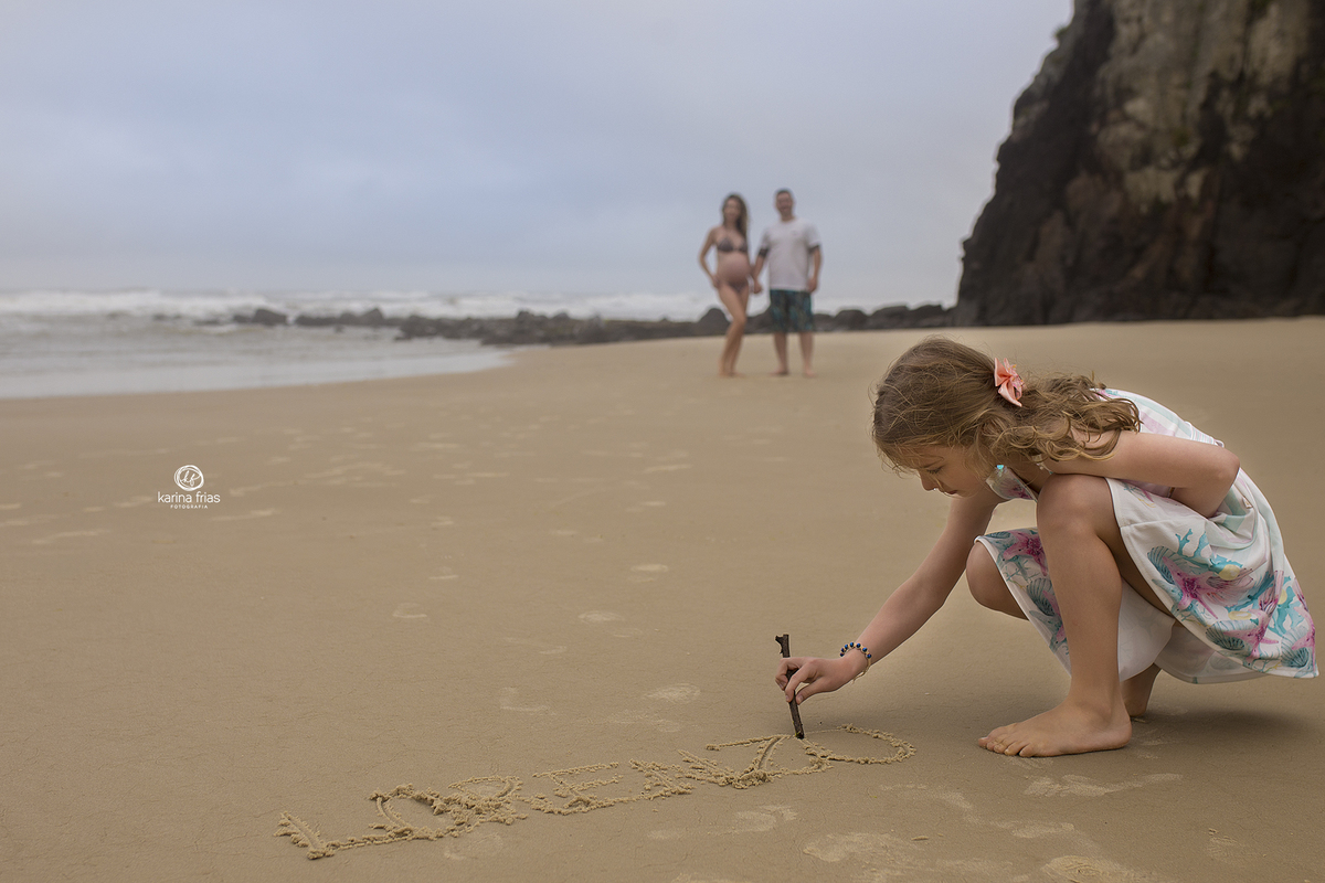 a menina escreve o nome do irmao na areia da praia