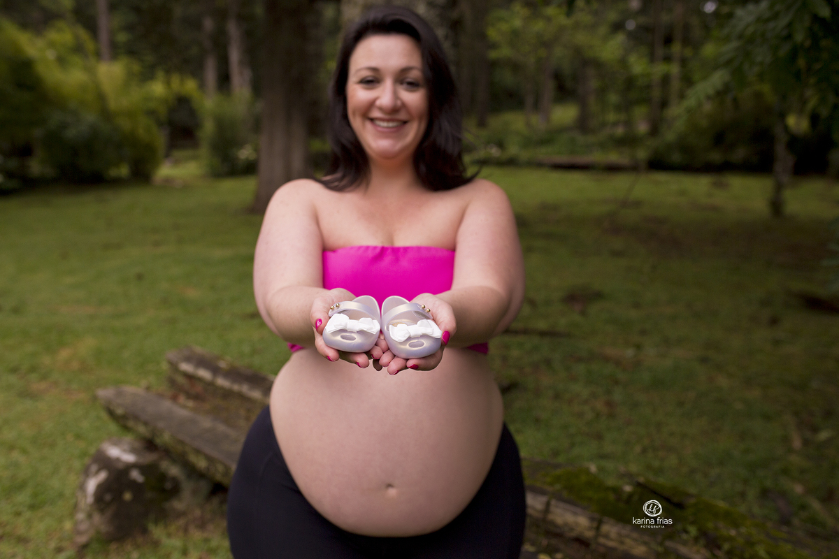 a gestante mostra os sapatinhos para a camera