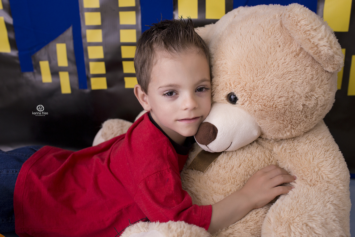 o menino abraça o urso no ensaio infantil