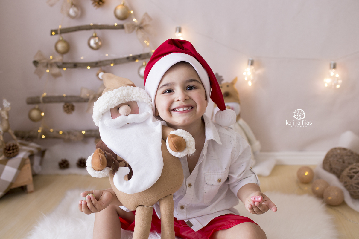 o menino abraça o papai noel ma sessão de natal