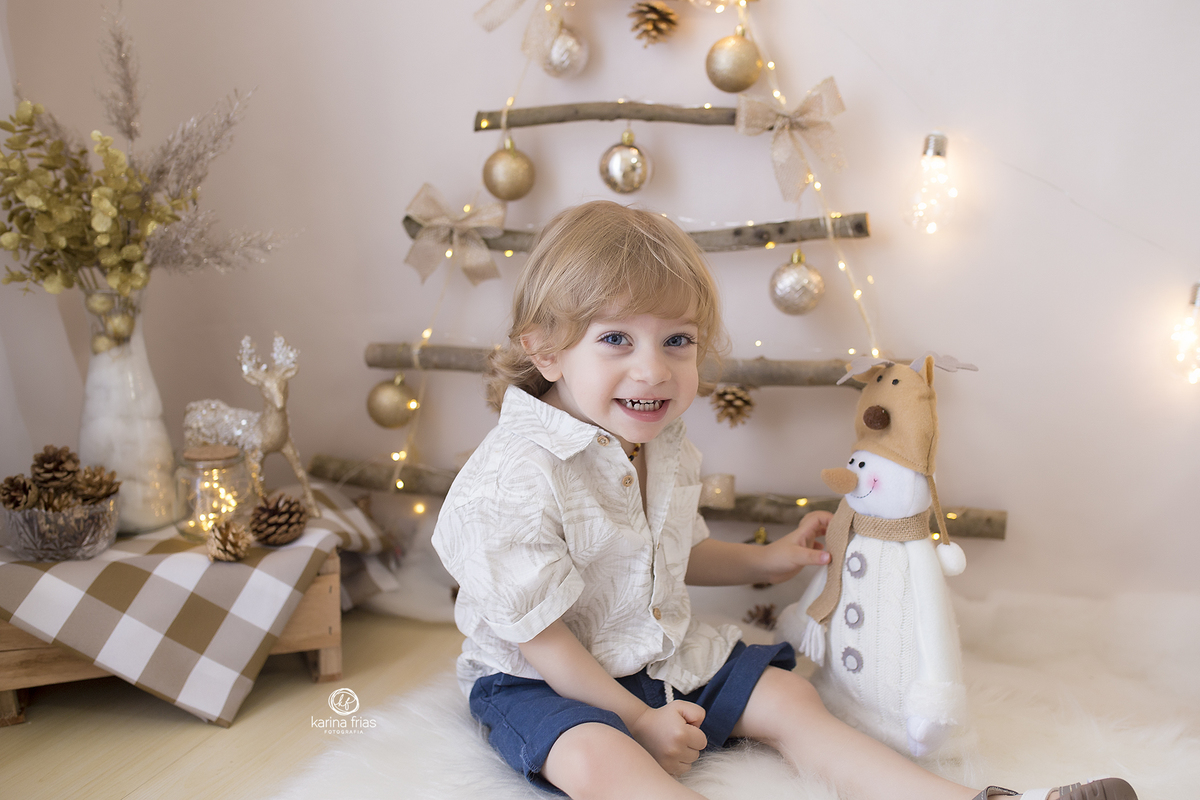 o menino esta sentado no cenario de natal