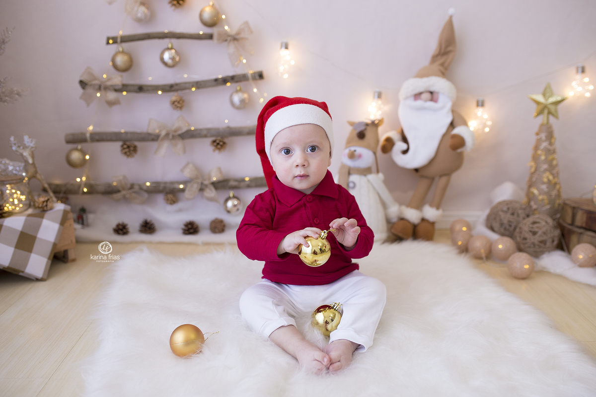 o menino esta no cenario de natal brincando com a bolinha