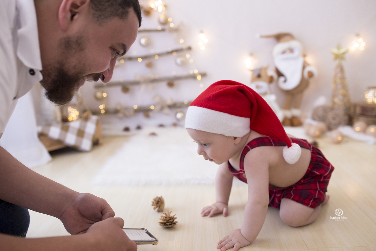 o menino olha atento para o celular do pai na sessão de fotos