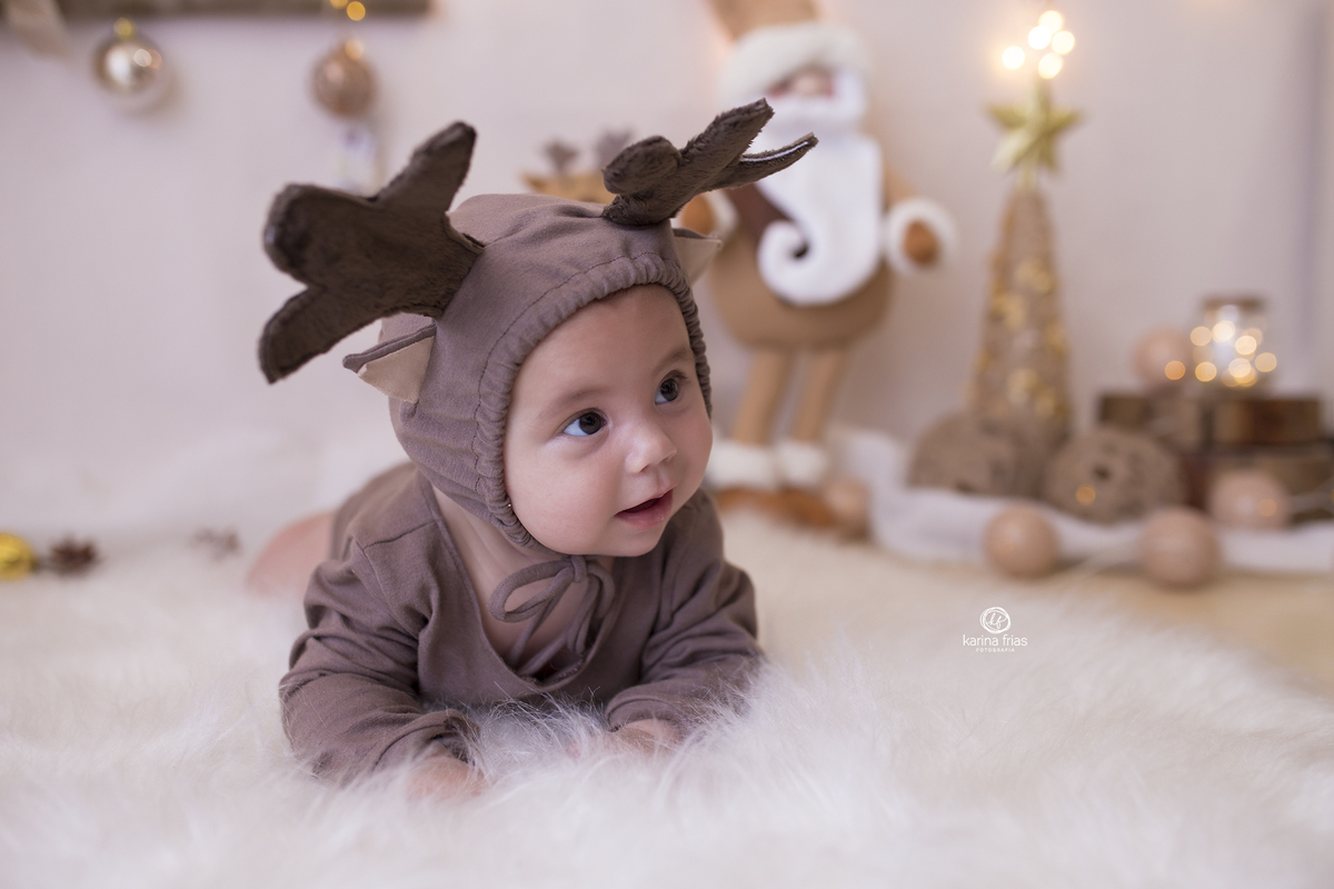 a bebe esta de bruços no cenario de natal