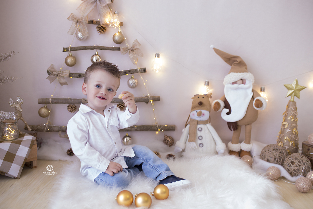 o menino esta sentado no cenario de natal